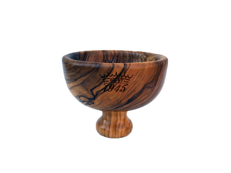 A wooden lathering bowl with a pedestal base, featuring a deeply grooved interior and intricate engravings on the side.